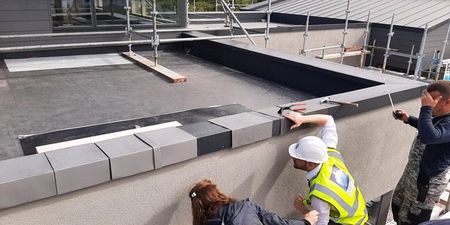 Gemma Inspecting Zinc Installation on Building